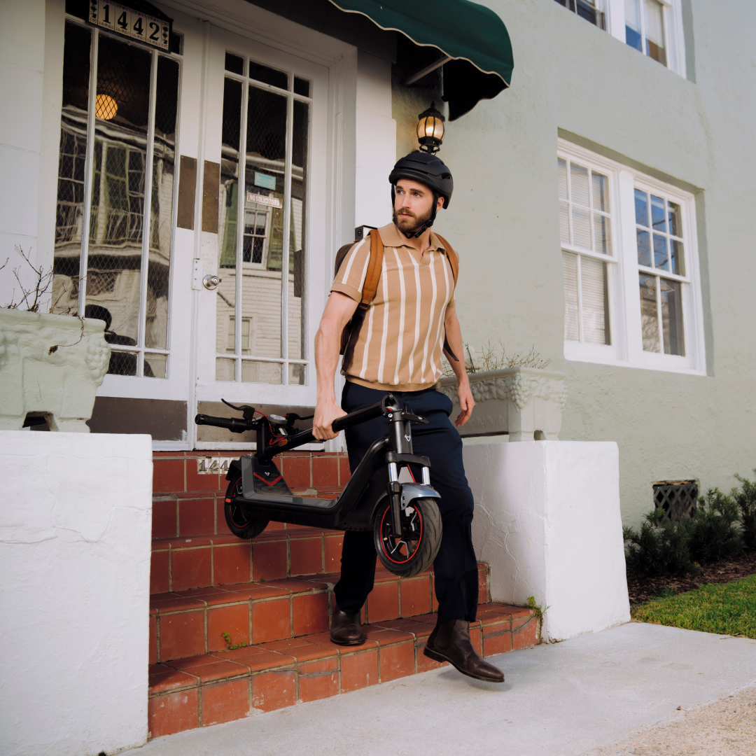 NIU KQi300X Electric KickScooter lifestyle photo, showing product being held by rider 
